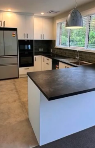 Modern kitchen design. White cabinets, black countertops, stainless steel appliances, and island. Kitchen trends and ideas.