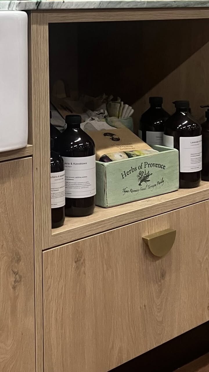 Bathroom beauty: minimalist wood cabinet with amber glass bottles, natural soaps, and Herbs of Provence box for a spa-like feel.