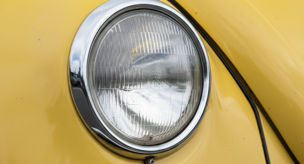 Classic car headlamp with chrome trim on a yellow body, featured in the January 2026 Quarterly Newsletter.