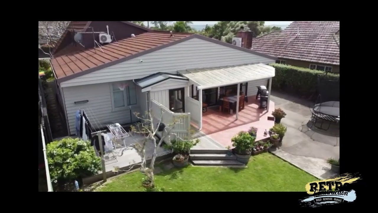 Home exterior showing structural transformation during a home renovation project, featuring a deck and backyard.